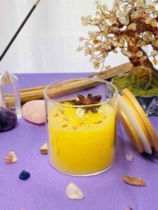 Vela de la abundancia encendida sobre un altar con elementos naturales, usada en rituales para atraer prosperidad y bienestar.